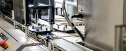 Automatyczna linia produkcyjna z elementami metalowymi, taśmociągiem i przyciskami. Kontekst: przemysł.