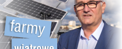 Mężczyzna w okularach stoi na tle farm wiatrowych i paneli słonecznych. Kontekst: energia odnawialna.
